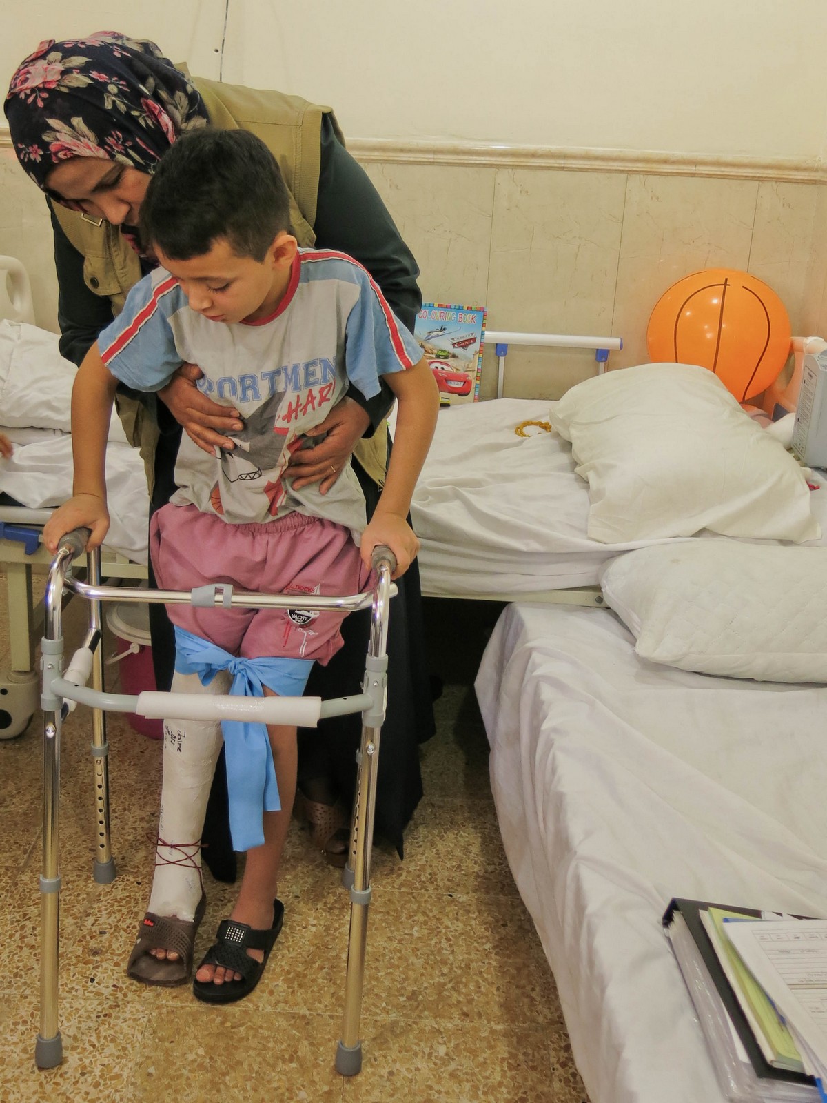 Hossam essaye de marcher à l'aide d'un déambulateur dans sa chambre d’hôpital à Hamdanyah © E. Fourt / Handicap International