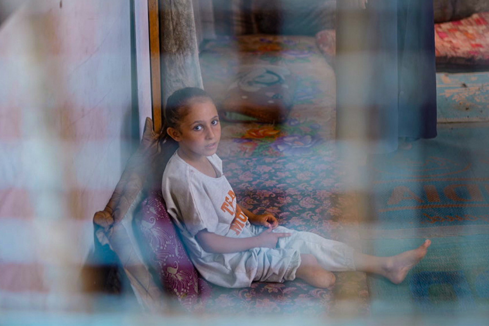Qamar, 7 ans, Gaza Une enfant avec une jambe amputée assis sur son canapé posé au sol