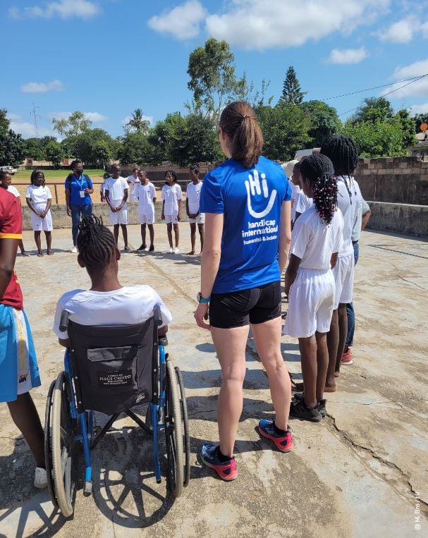 une personne en fauteuil à coté d'une autre avec un tshirt HI