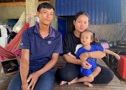 Au Cambodge, un père et une mère posent dans leur maison avec leur petite fille de 3 ans, qui est dans les bras de sa mère.