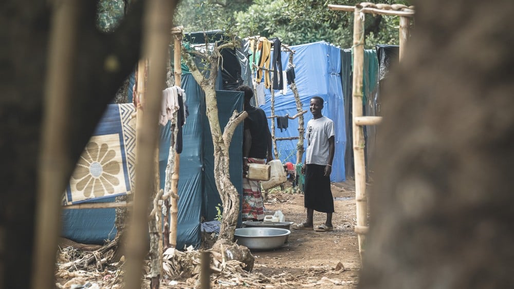 Dans un camp de fortune à Mayotte, un homme se retourne et sourit au photographe.