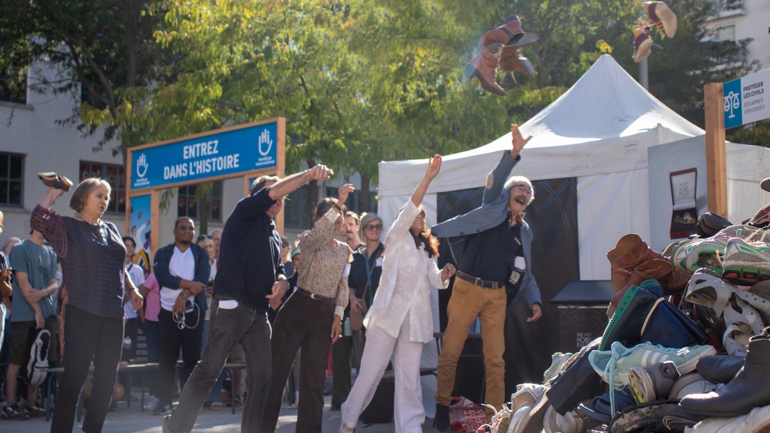 Des personnes lancent des chaussures sur une Pyramide de Handicap International.