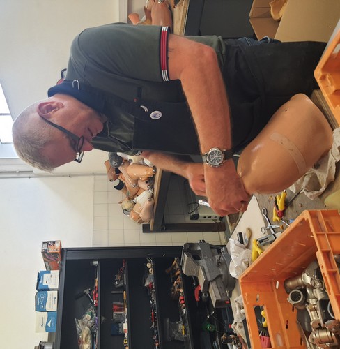 Dans un atelier, un homme démonte une prothèse de jambe.