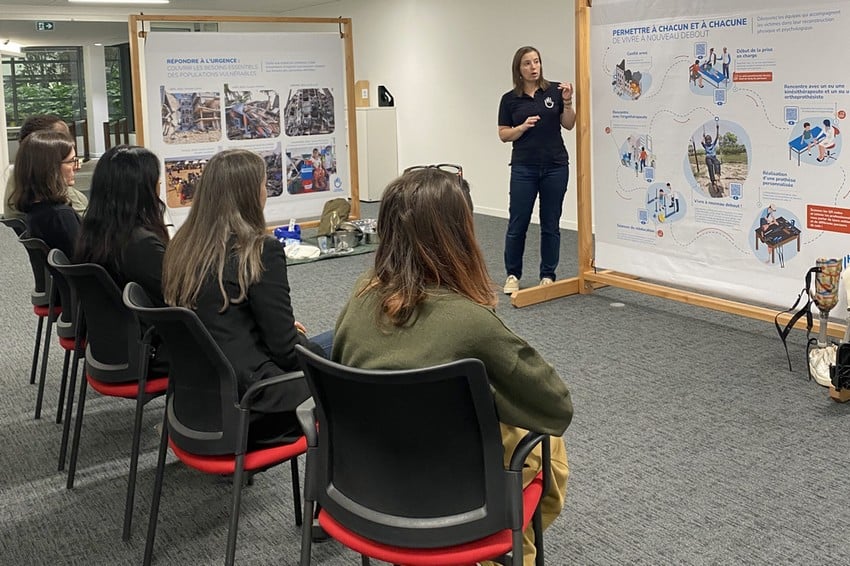 devant quelques personnes assises, une personne fait une présentation à l'aide de panneaux.