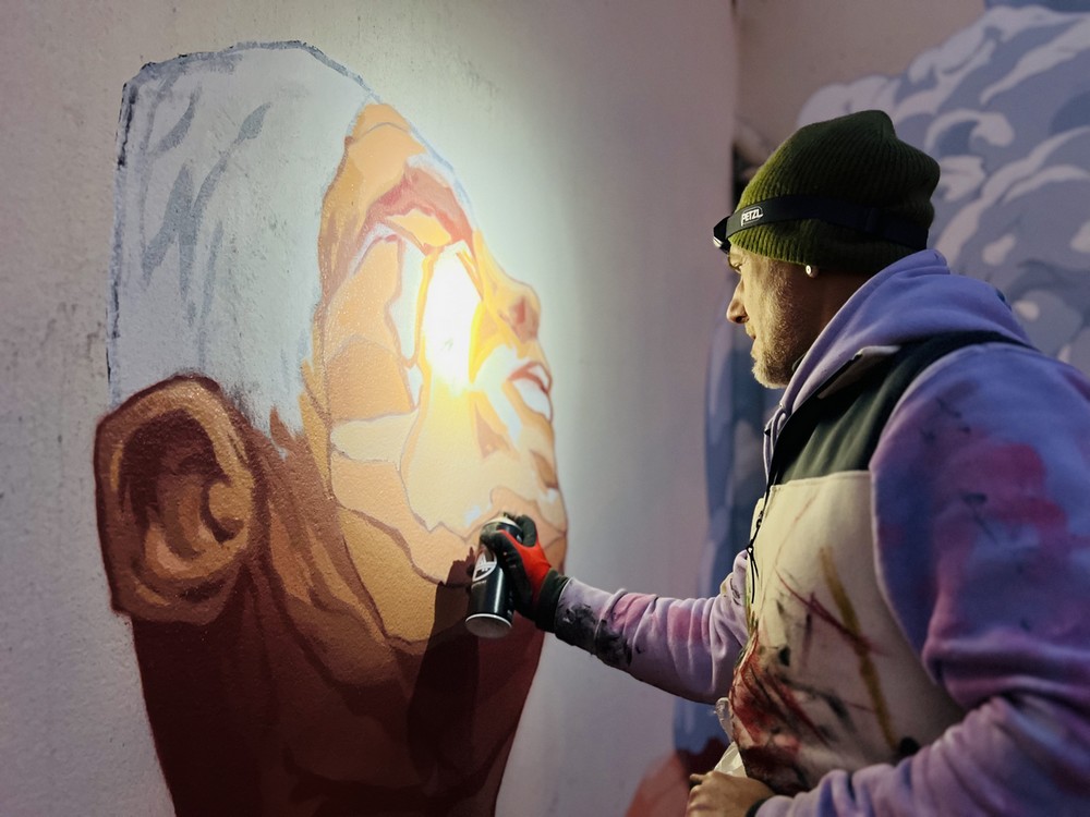 L'artiste Brusk en train de réaliser une fresque murale