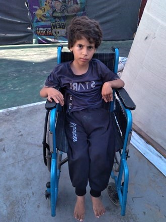 Une petite fille de 8 ans assise dans son fauteuil roulant regarde le photographe.
