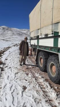 Dans une zone montagneuse, sur une route enneigée, un homme se tient debout à côté d'un camion.
