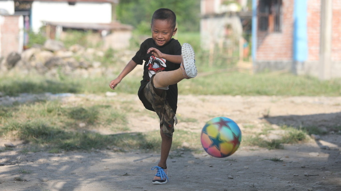 Prabin, 6 ans, joue au football au Népal avec sa prothèse.