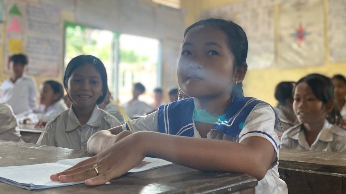 Une jeune fille assise sur son banc à l'école au Cambodge