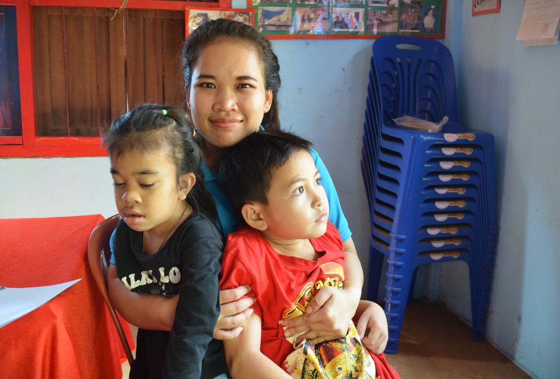 Au Laos, une jeune femme prend dans ses bras deux enfants, une fille et un garçon.