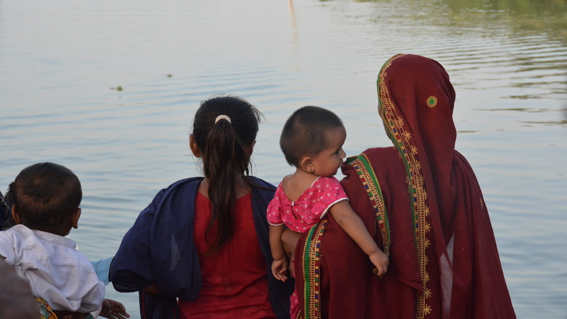 Une femme et des enfants regardent dans la direction d’un village inondé au Pakistan. © Development Tales Media / HI