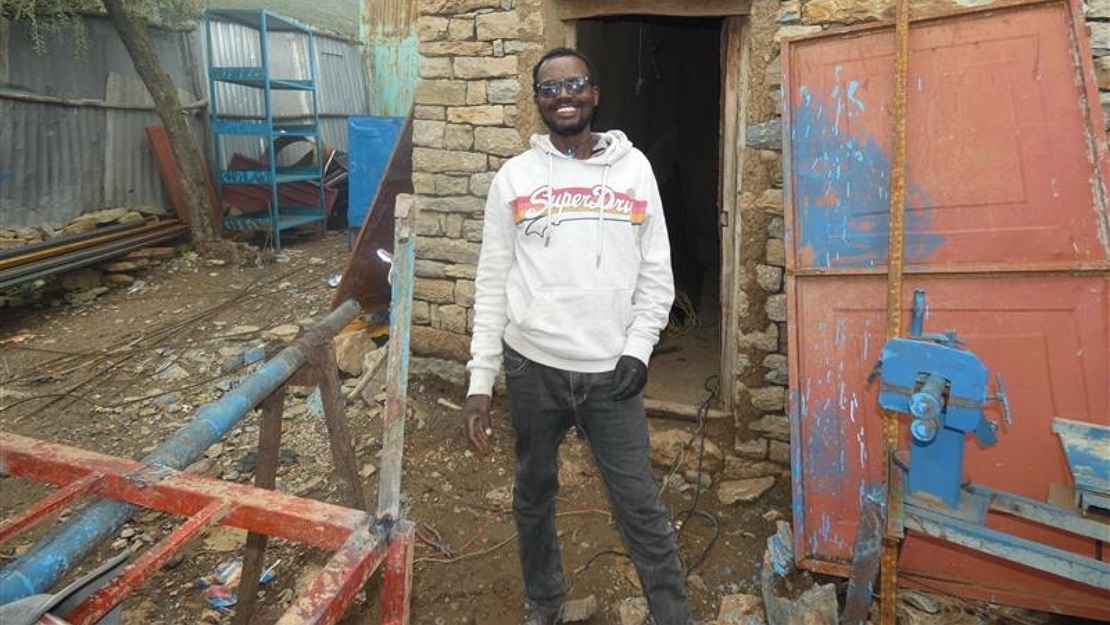 Un jeune homme se tient devant l'entrée de son atelier en Éthiopie.