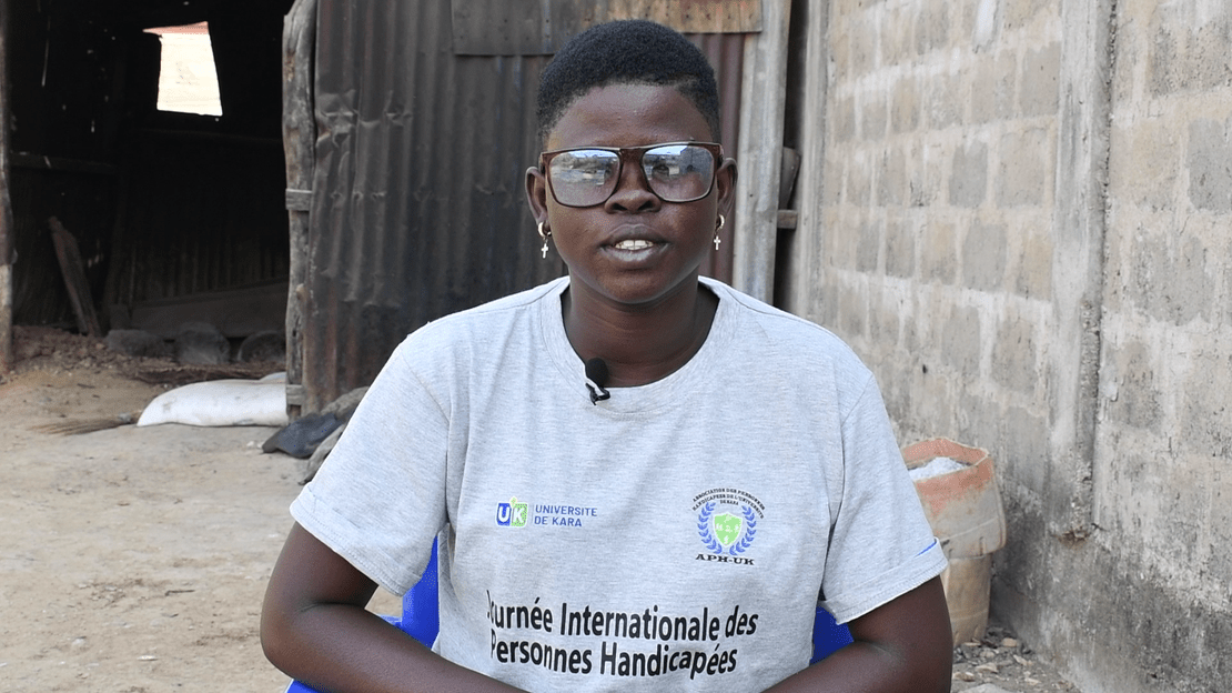 Portrait en gros plan d'une jeune fille portant des lunettes, assise sur une chaise. elle porte un t-shirt avec l'inscription 