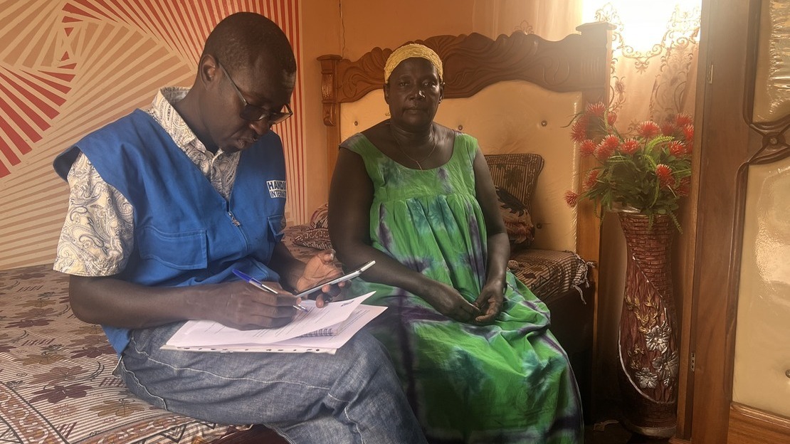 Un homme et une femme sont assis sur un canapé. Sur la gauche, l'homme est penché sur ses notes. Sur la droite, la femme regarde le photographe.
