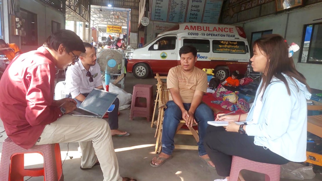 Quatre personnes dans un garage devant une ambulance.