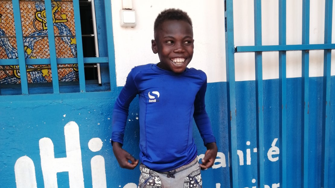 Un petit garçon se tient debout devant l’hôpital régional de Bambari en République Centrafricaine et montre sa prothèse.