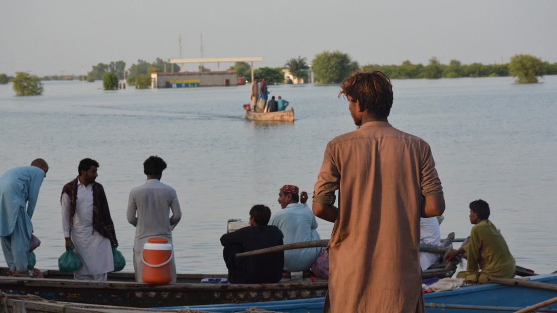 Un jeune homme se tient debout devant l'étendue d'eau causée par les inondations au Pakistan.