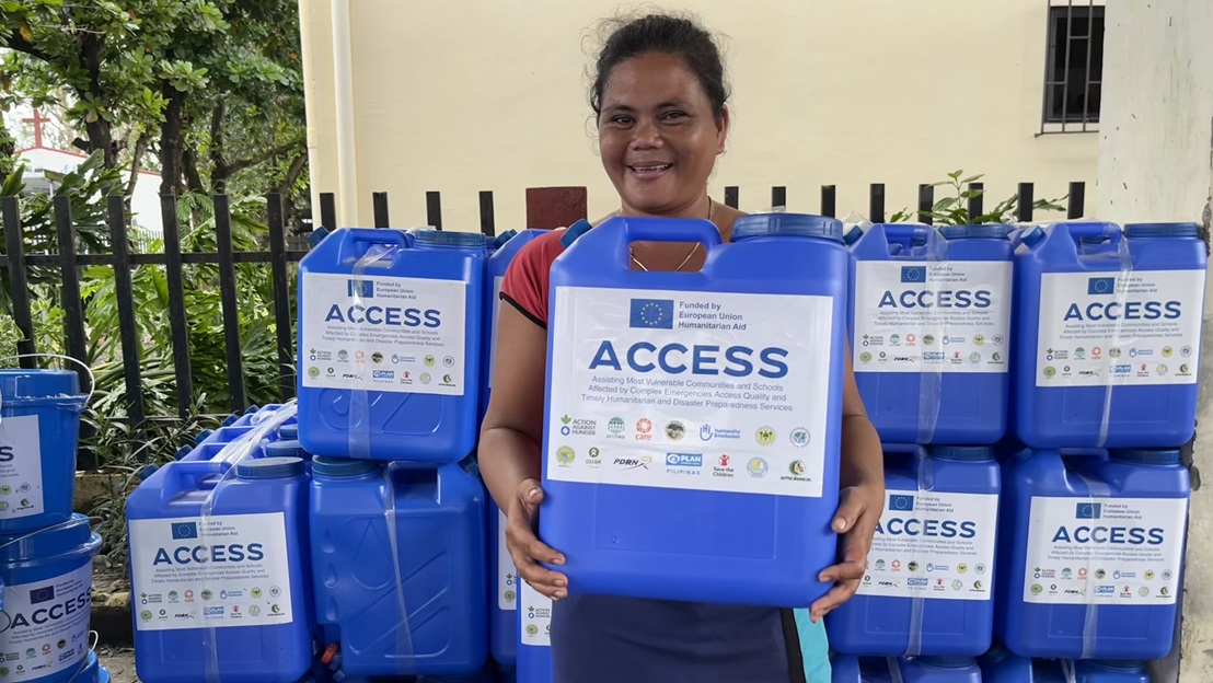 Une jeune femme reçoit un jerrycan d'eau lors d'une distribution d'aide humanitaire.
