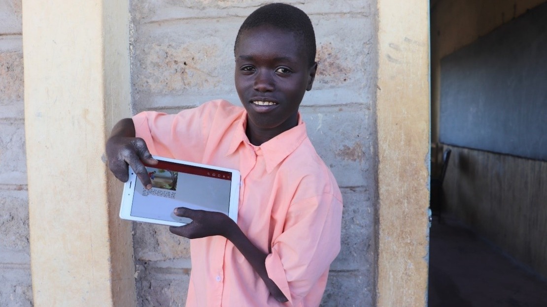 Patrick montre l'histoire qu'il vient de lire sur sa tablette grâce à une classe numérique à Kakuma au Kenya