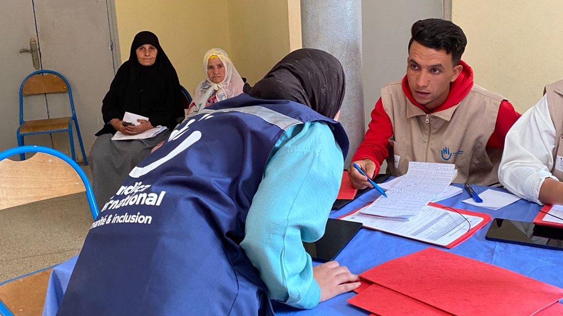 Deux membres de l'équipe sont à l'accueil de la caravane organisée, des bénéficiaires attendent d'être prises en charge.