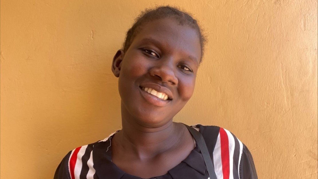 Portrait d'une jeune femme qui sourit devant un bâtiment.