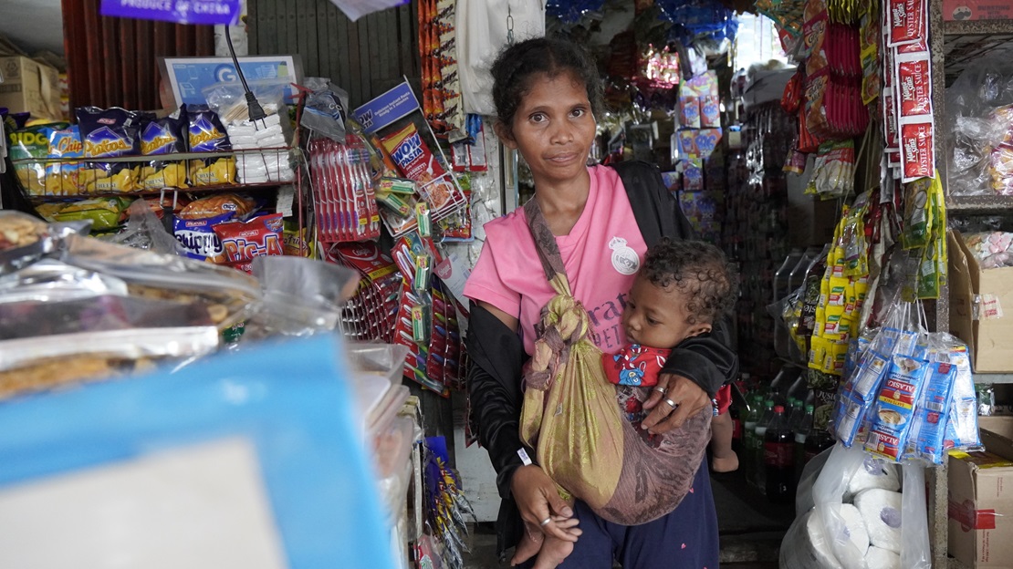 Une jeune femme porte son bébé dans un magasin aux Philippines.