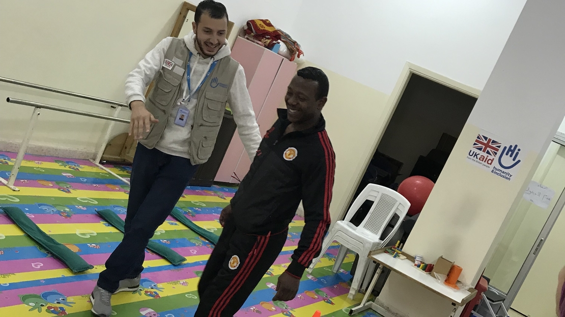 Amer fait ses exercices d'équilibre avec le kiné de Handicap International