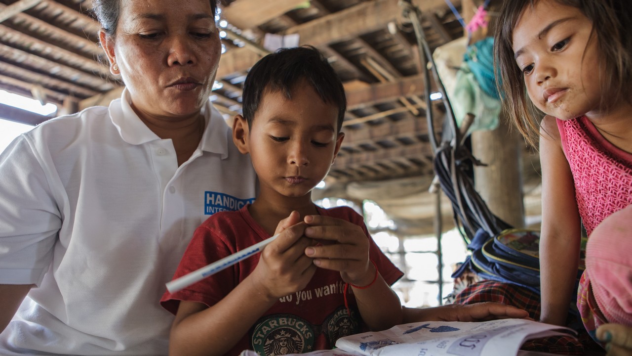 Davann, agent social de Handicap International, avec Sovannareach, un jeune patient du centre de réadaptation de Kampong Cham