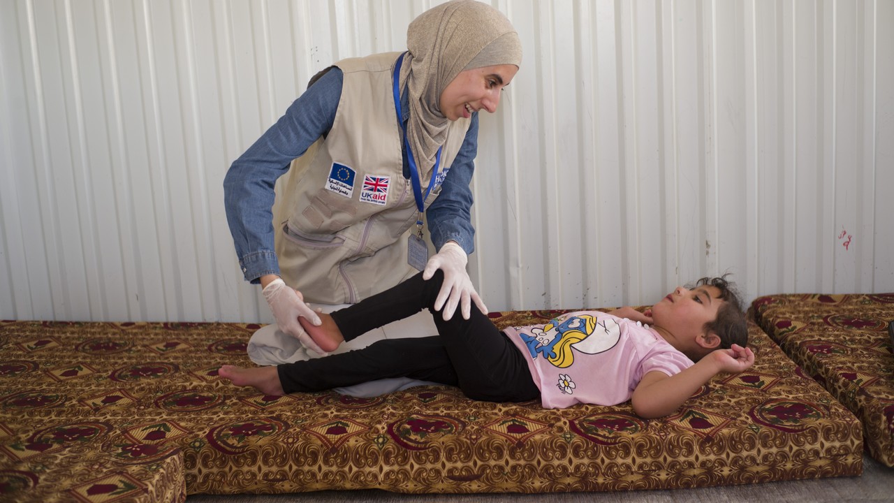 Noor, kiné de Handicap International, lors d’une session dans le camp d’Azraq avec Hala, une fillette qui souffre de paralysie cérébrale.