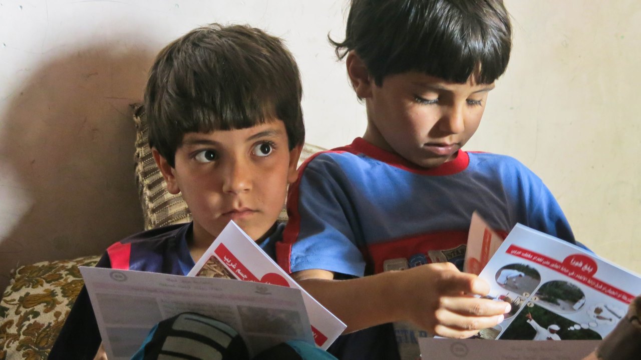 En Irak, deux frères regardent les prospectus laissés par l’équipe de Handicap International à la fin d’une session d'éducation aux risques des mines.