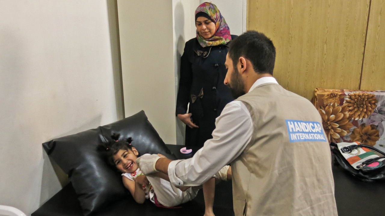 Afra et sa maman Dari pendant une séance de réadaptation prodiguée à la fillette par Mohammad de Handicap International