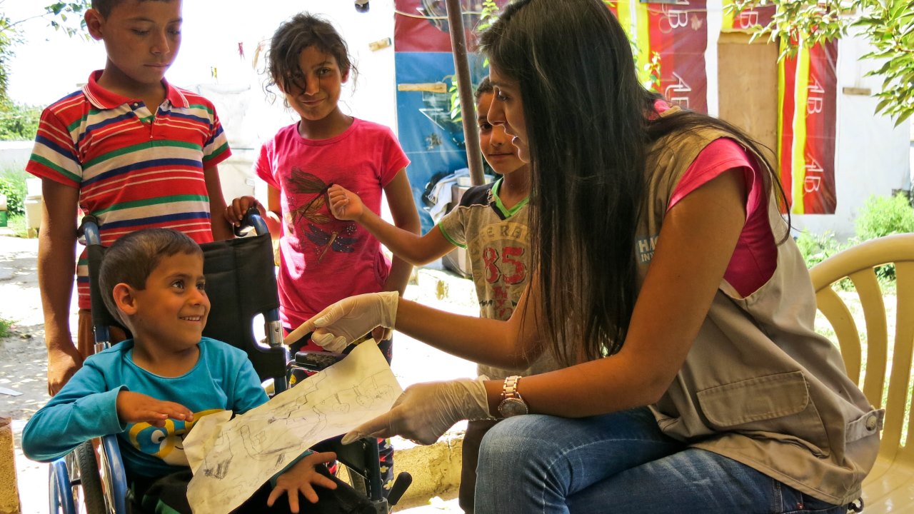 À la fin de la session de kinésithérapie, Zoheir montre l’un de ses dessins à Cynthia, kinésithérapeute de Handicap International