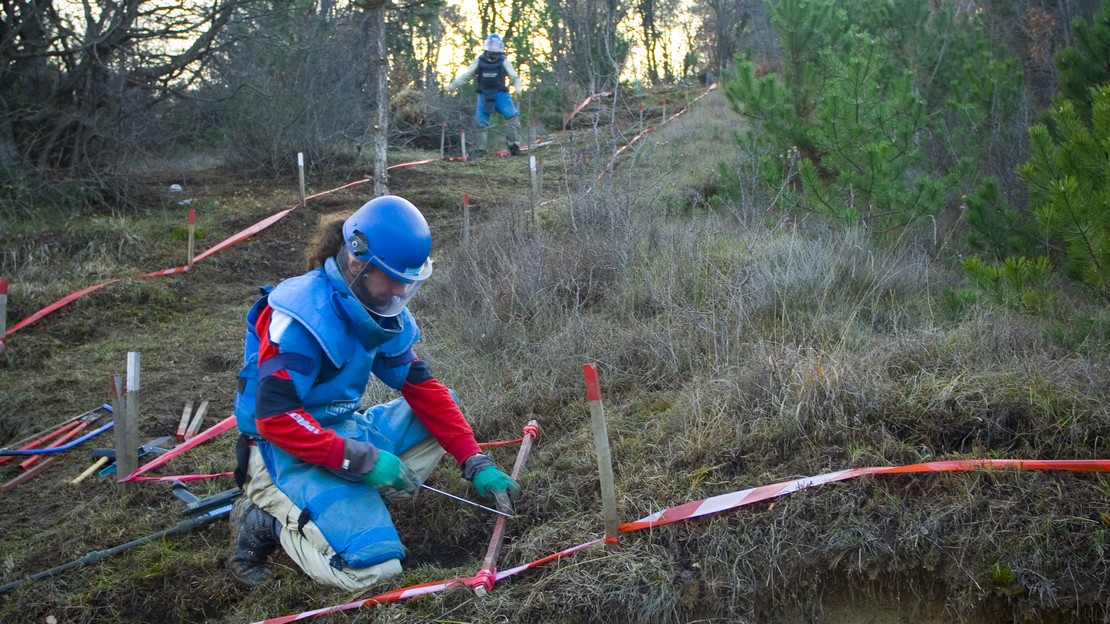 Démineurs en train de travailler sur un terrain accidenté.