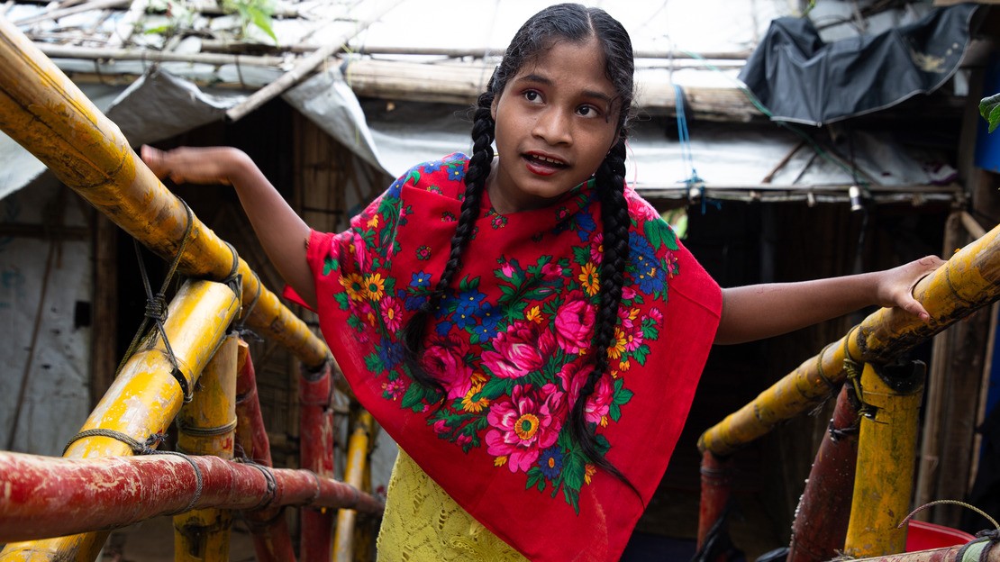 Une jeune fille monte les escaliers à la sortie de son abri dans un camp de réfugiés, aidée par les rampes d’accès.