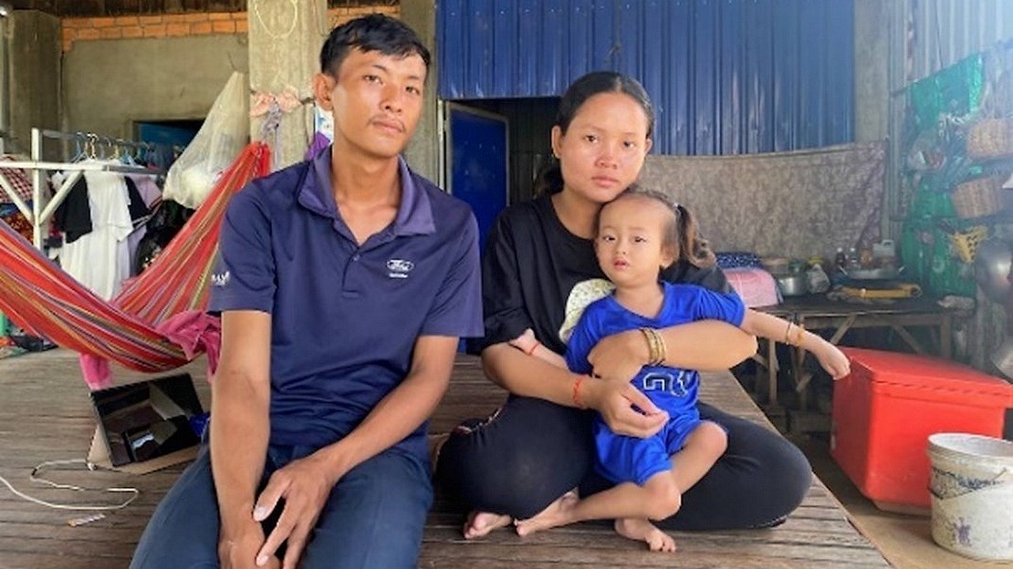 Au Cambodge, un père et une mère posent dans leur maison avec leur petite fille de 3 ans, qui est dans les bras de sa mère.