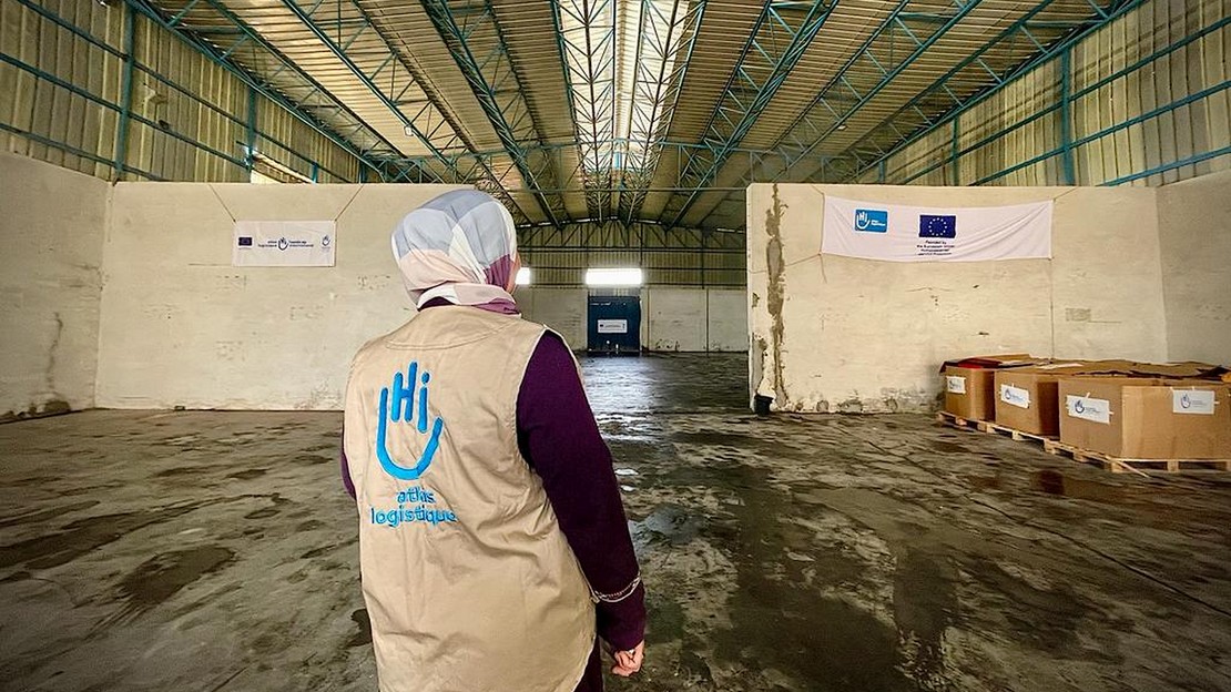 Une femme de dos se tient debout dans un entrepôt presque vide.