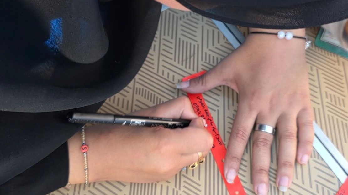 Une mère de famille inscrit ses coordonnées sur un bracelet.