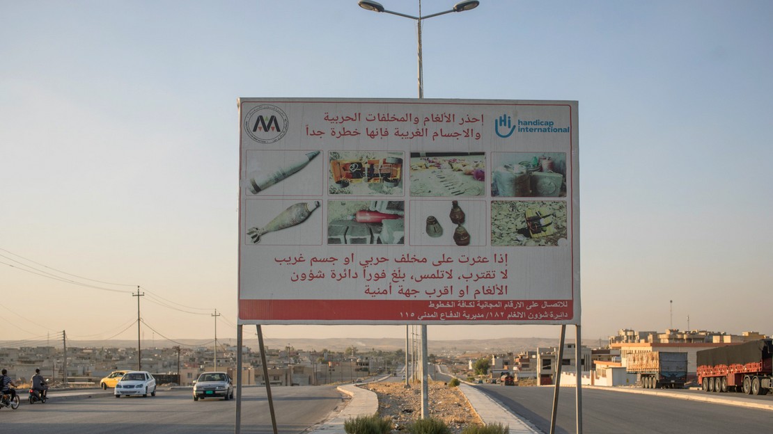 À l'entrée de Mossoul en Irak, un panneau de Handicap International sensibilise la population aux dangers liés à la présence de restes explosifs de guerre partout dans la ville