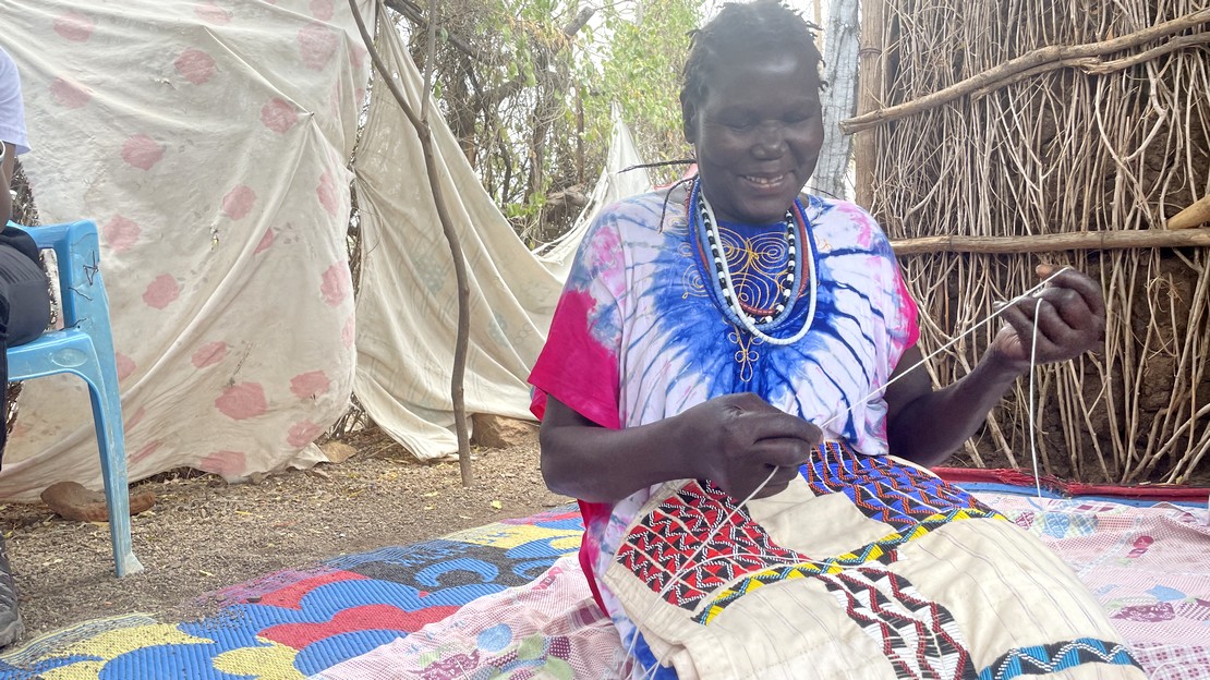 Au Kenya, Thwol en train de broder un tissu avec des perles.
