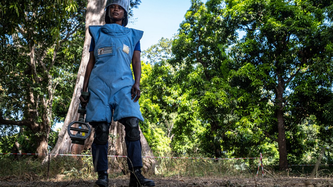 Une femme en tenue de démineuse se tient debout dans une forêt.