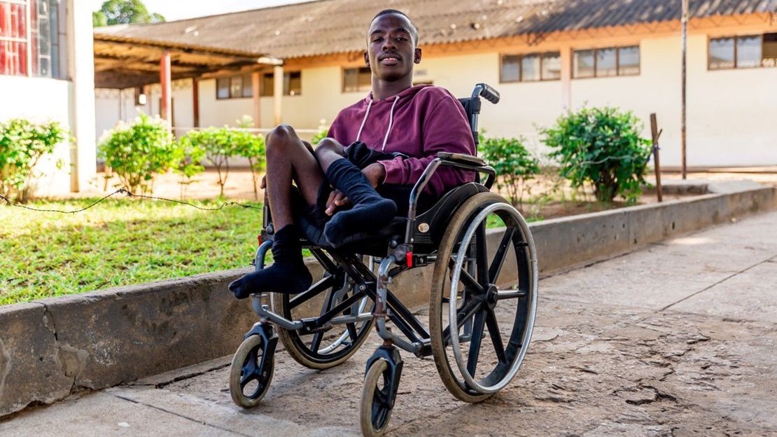 Un jeune étudiant de Madagascar est assis dans on fauteuil roulant.