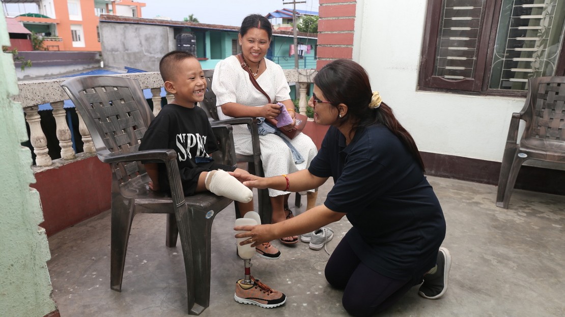 Jeune enfant au Népal équipé d'une prothèse, avec l'orthoprothésiste qui s'occupe de lui.