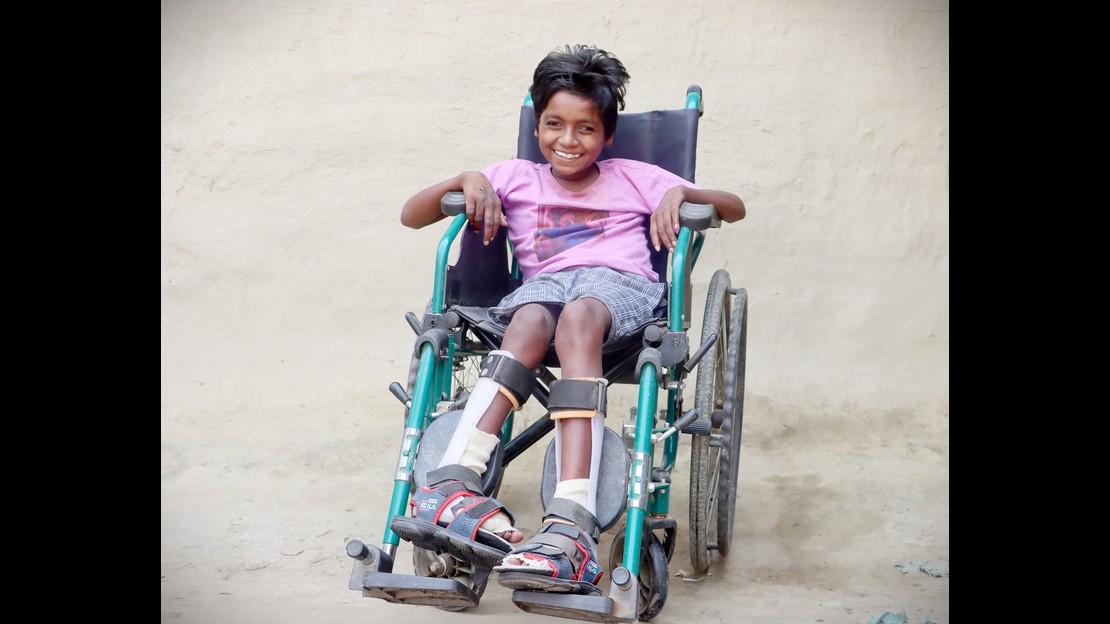 Une jeune fille dans un fauteuil roulant sourit au photographe.
