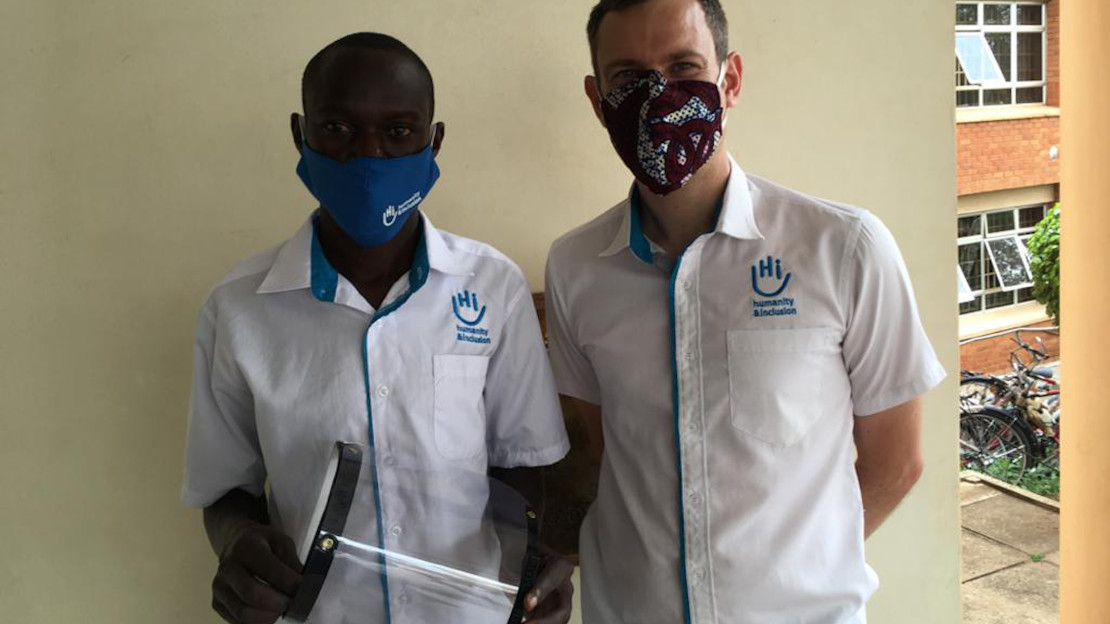 Disan (à gauche sur la photo), technicien d’impression 3D à Handicap International en Ouganda, présente une visière réalisée grâce à la technologie 3D.