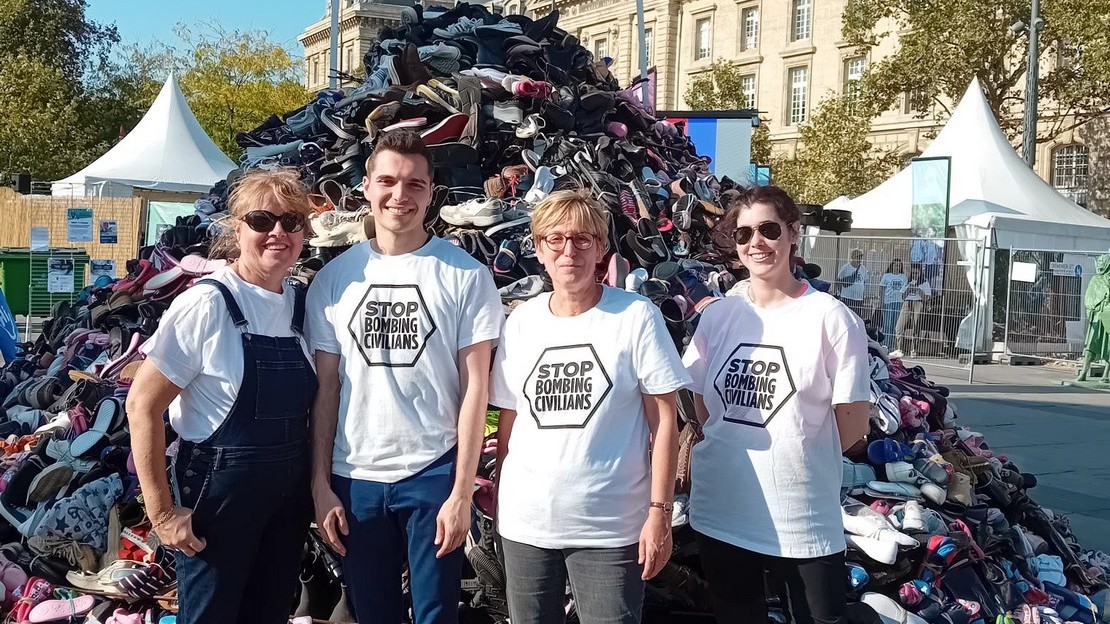 Des bénévoles se tiennent debout devant la Pyramide de chaussures de Handicap International à Paris en septembre 2024.