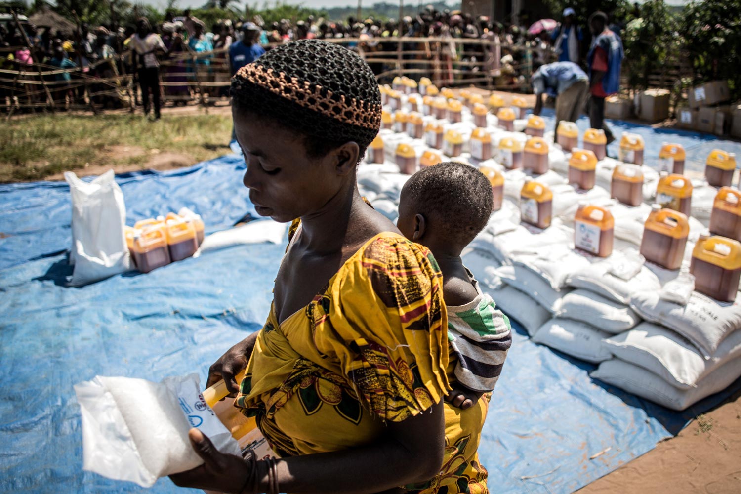Une bénéficiaire porte son bébé dans un site de distribution de HI et du programme Food For Peace