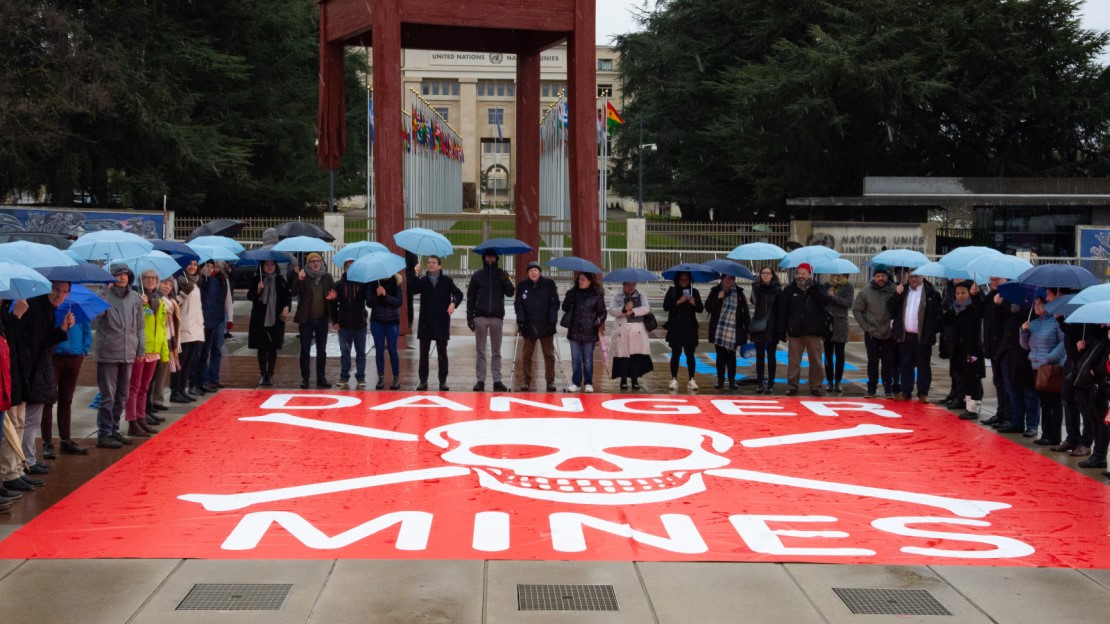 Un groupe de personnes devant le monument broken chair et un drapeau 