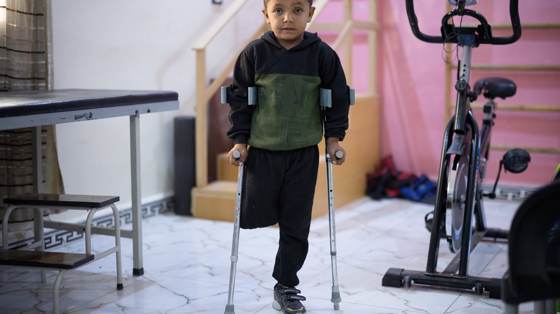 Un jeune Syrien de 8 ans, amputé de la jambe droite, pose debout avec ses béquilles et regarde le photographe avec un air triste.