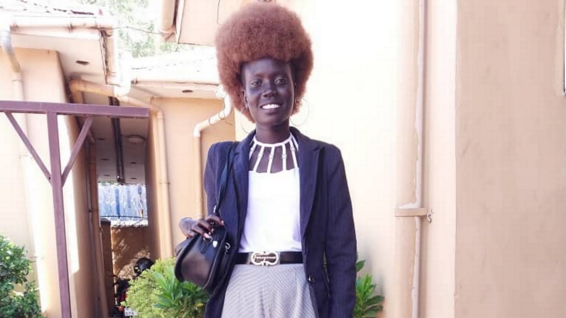 Une femme se tient debout devant un immeuble.