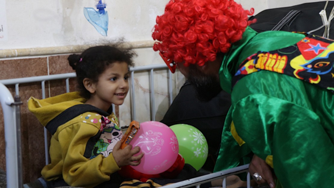 Une petite fille à l'hôpital joue avec un personnel associatif déguisé en clown